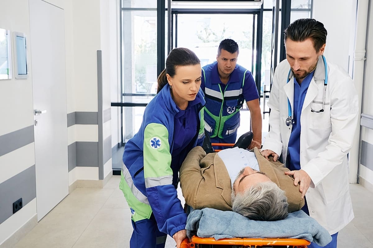 Paramedics and doctor rushing with victim patient on ambulance stretcher on hospital corridor at emergency department.