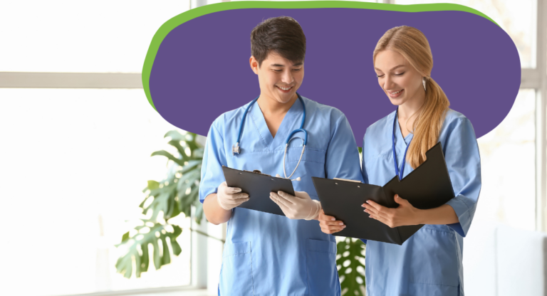 two medical residents wearing blue scrubs looking at patient charts.