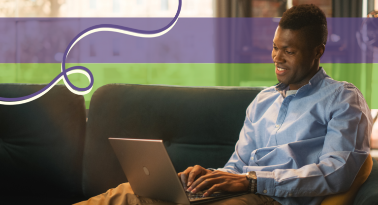 African American man sitting on a couch with a laptop on his lap.